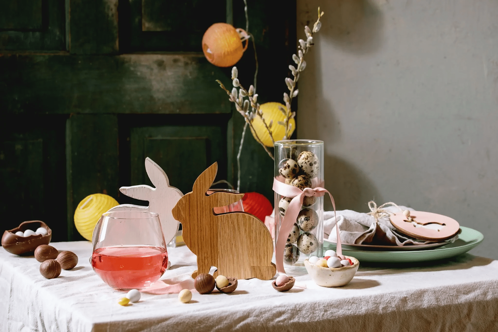 Mesa posta com decoração de Páscoa: coelhinhos de madeira, ovinhos e enfeites coloridos.