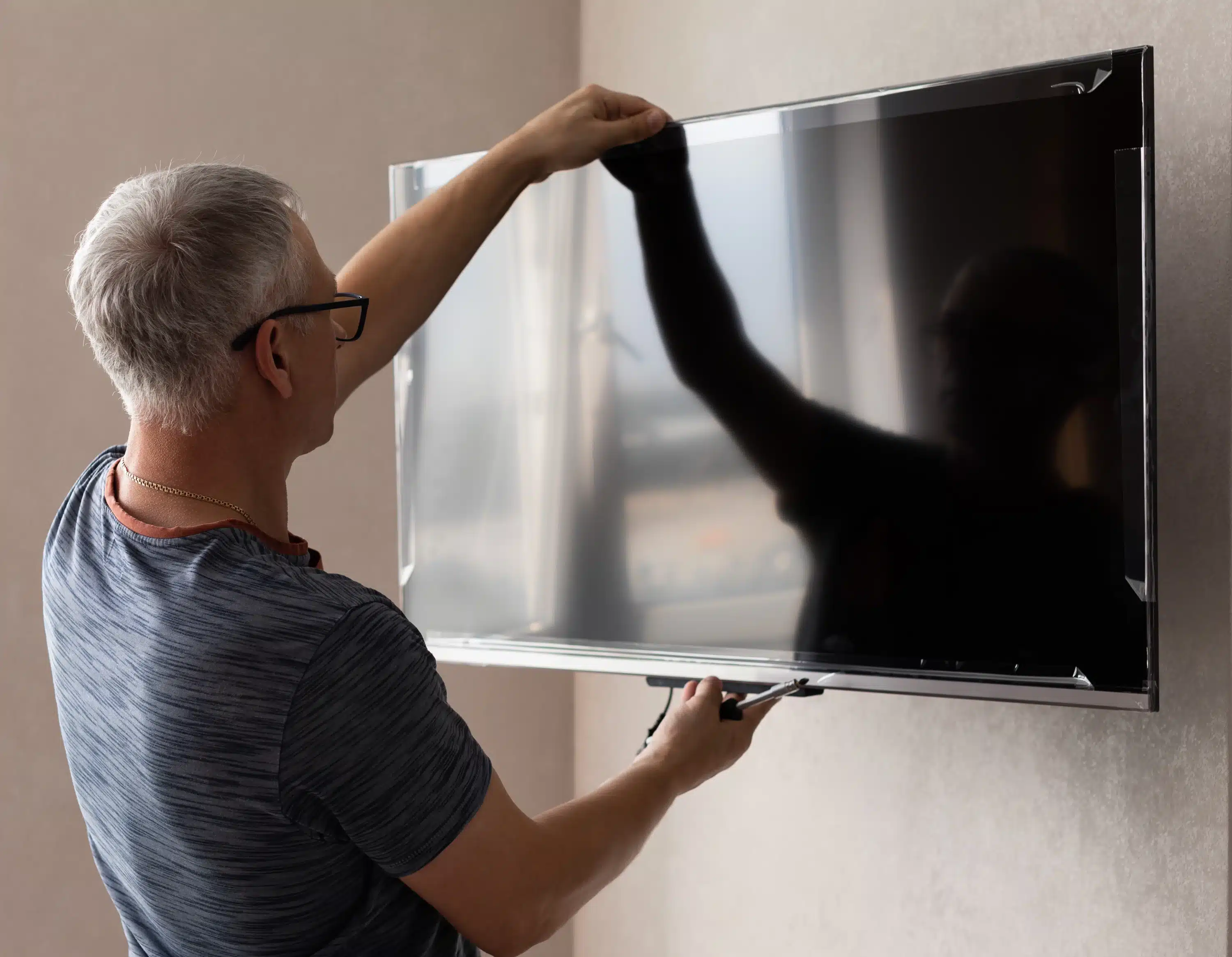 homem colocando tv na parede com suporte de tv